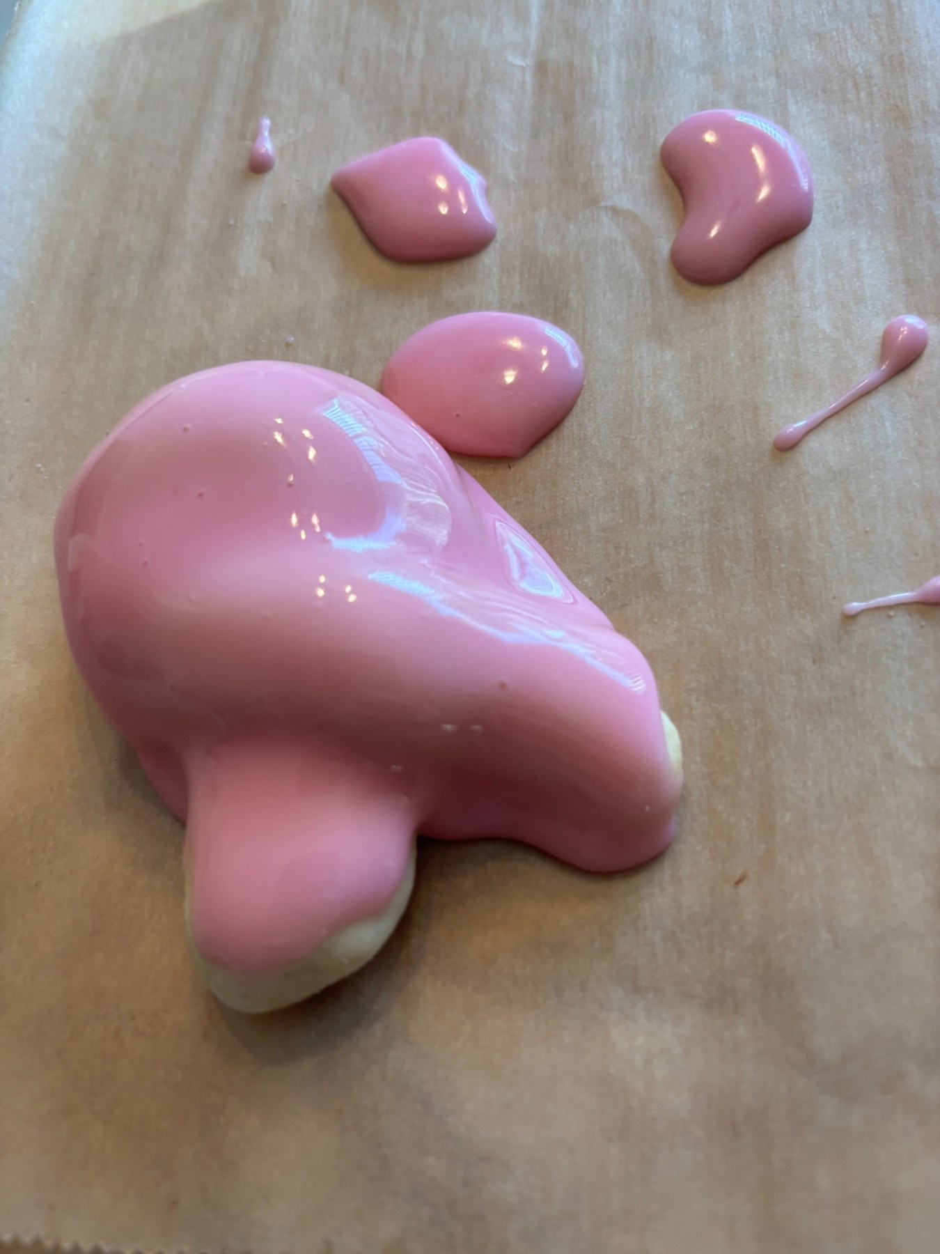A freshly glazed pink lemon Knot cookie on parchment